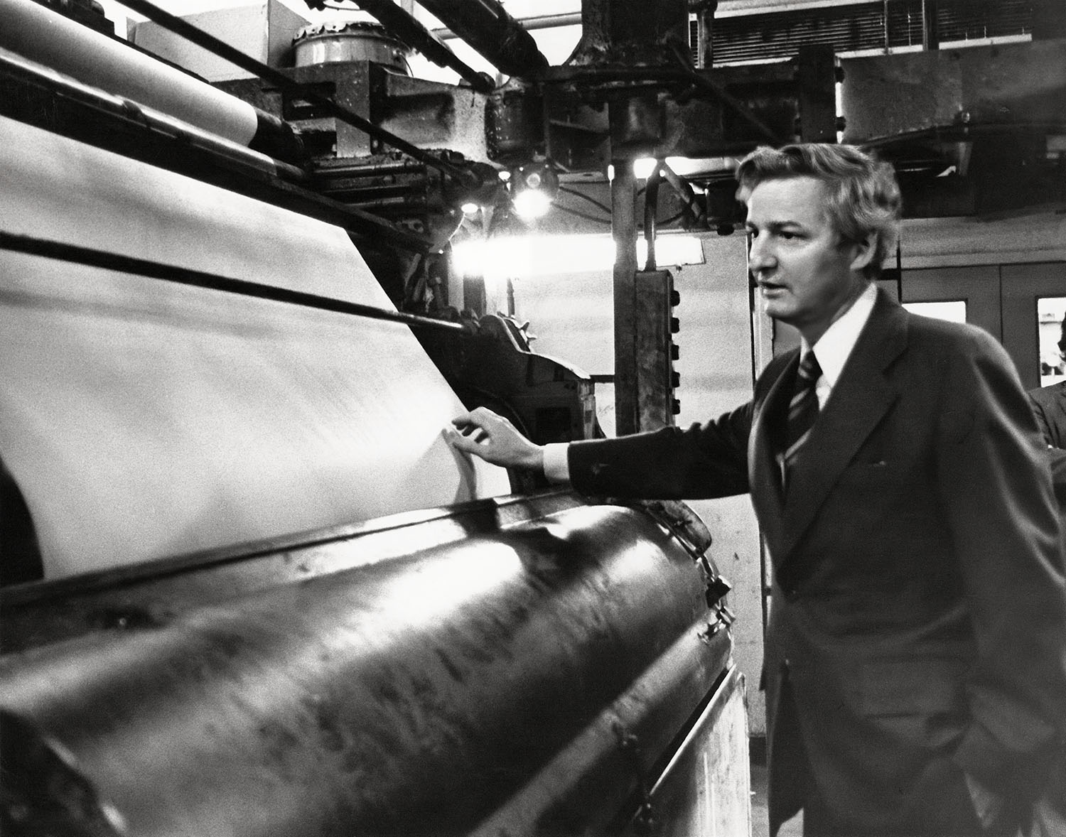 Photograph of Paul Desmarais, Sr. next to a printing press